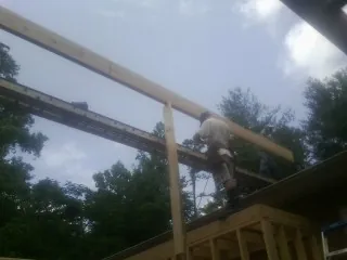 Carpenter setting a ridge beam over a new addition frame — Ice Dam Removal by Roofing Brothers in Mayetta