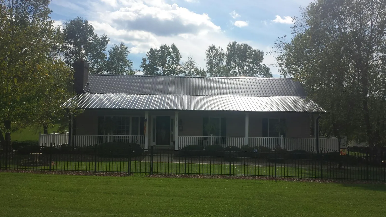 Gray metal roof on a brick ranch with a full width front porch — Gutter Guard Installation work by our crew in Mayetta