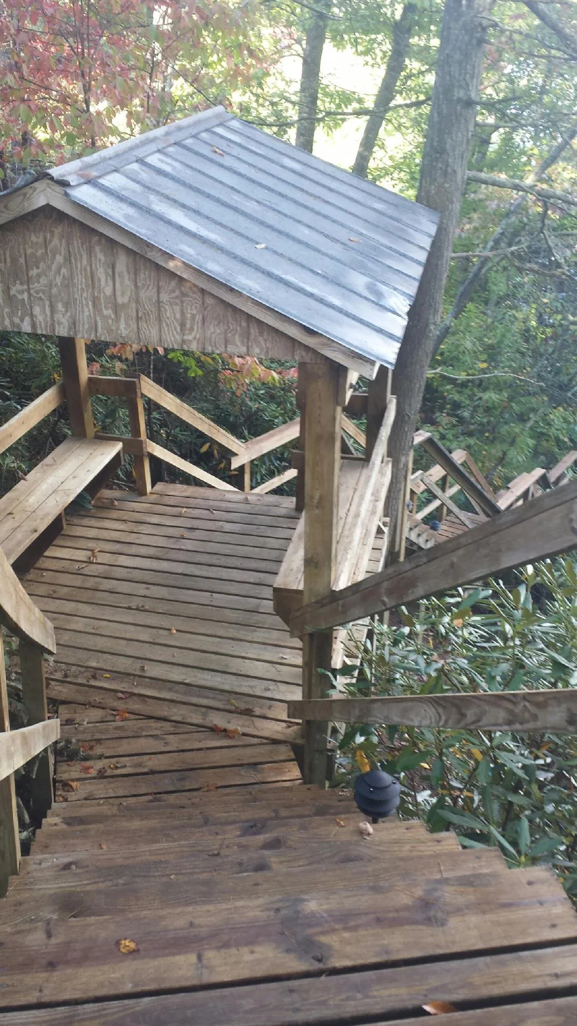Metal roofed shelter over wooden steps on a wooded walkway — Skylight Repair & Installation work by our crew in Mayetta