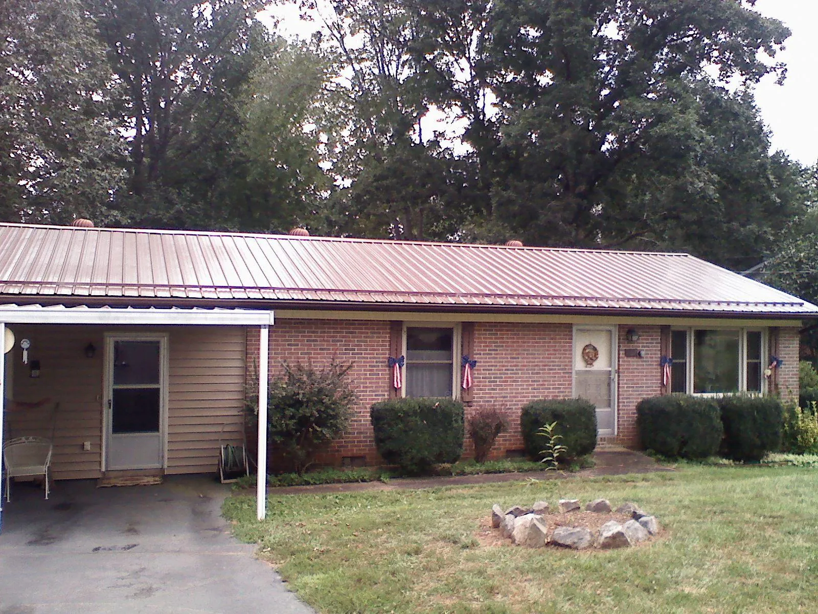 Bronze metal roof and carport on a brick ranch home — Roof Repair work by our crew in Mayetta