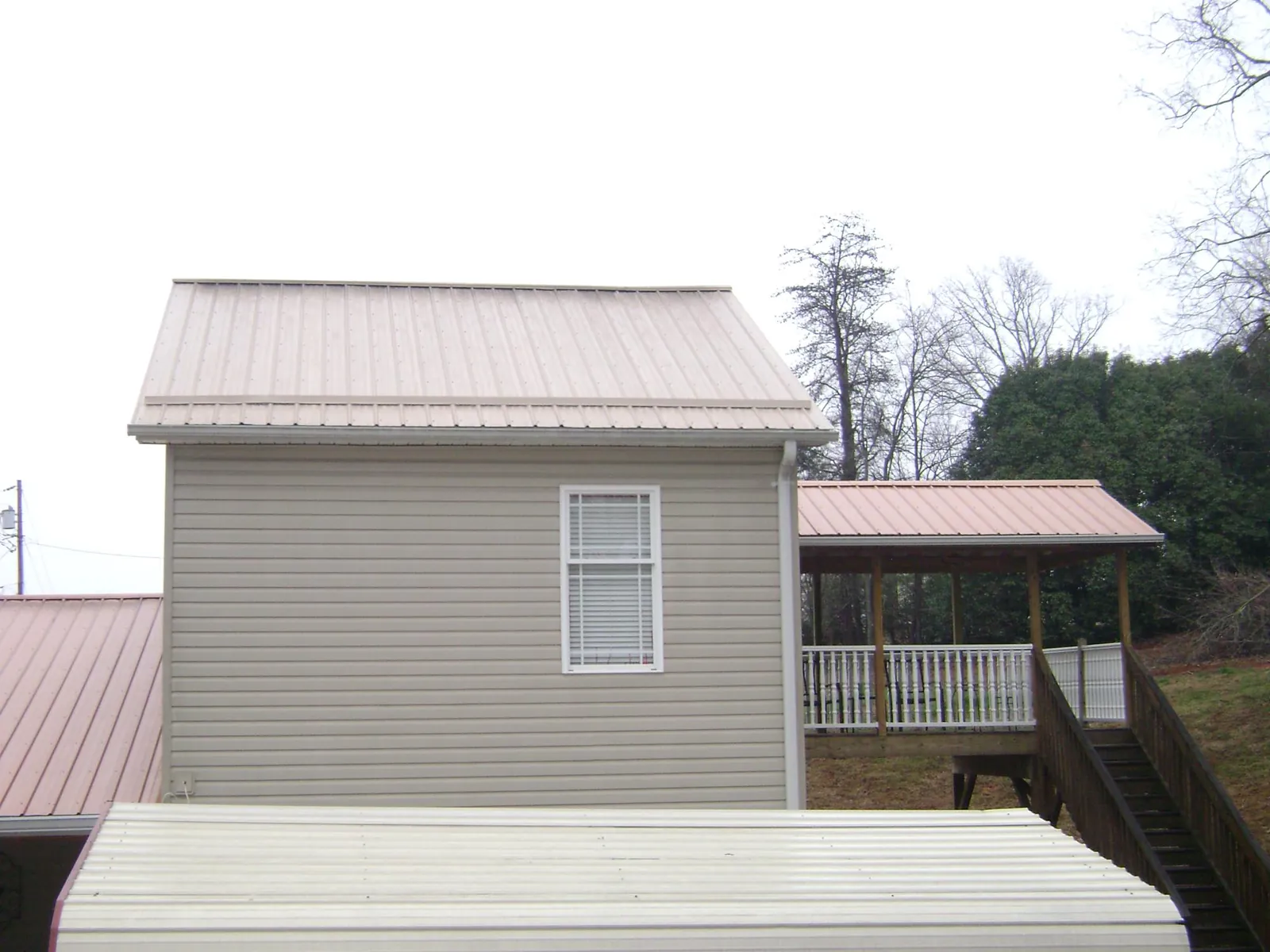 Tan metal roofs on a two story addition and attached porch, from a Roof Replacement job in Mayetta