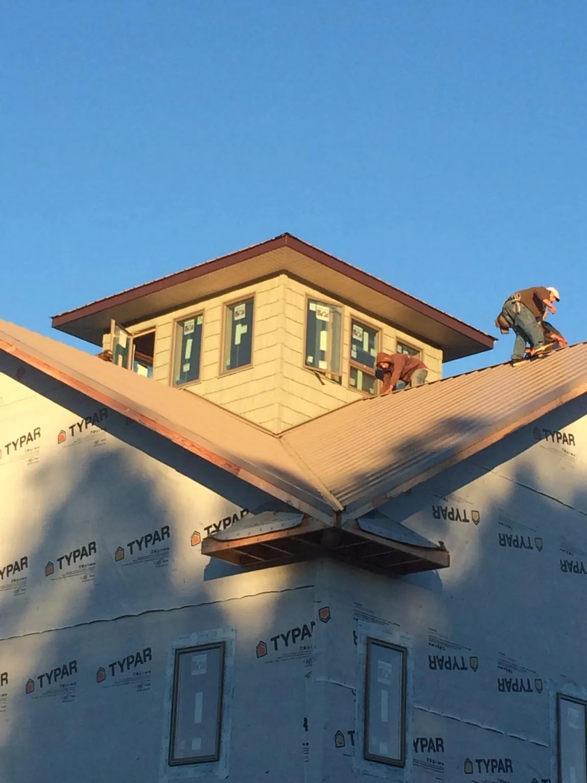 Roofers working around a rooftop cupola on a new metal roof at sunset — Roof Waterproofing in Mayetta by Roofing Brothers
